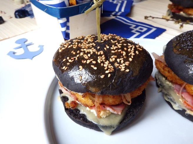 Burger breton recette terre et mer avec des buns à l'encre de sèche, lard, poisson pané, et mayonnaise façon sauce au beurre blanc