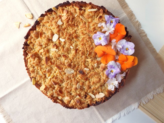 Crumble aux pommes et au chocolat dans une pâte sablée aux spéculoos avec des fleurs de pensées